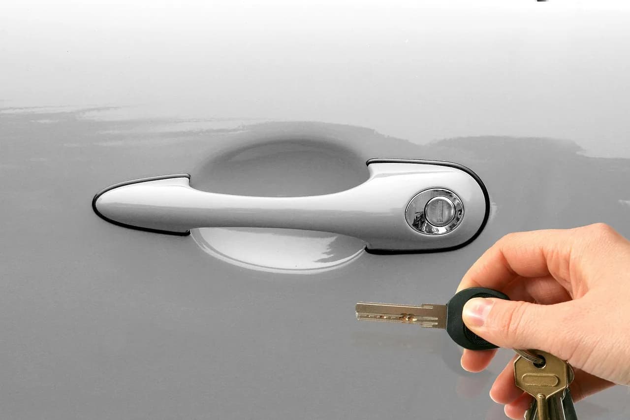 A car key held at a vehicle door handle
